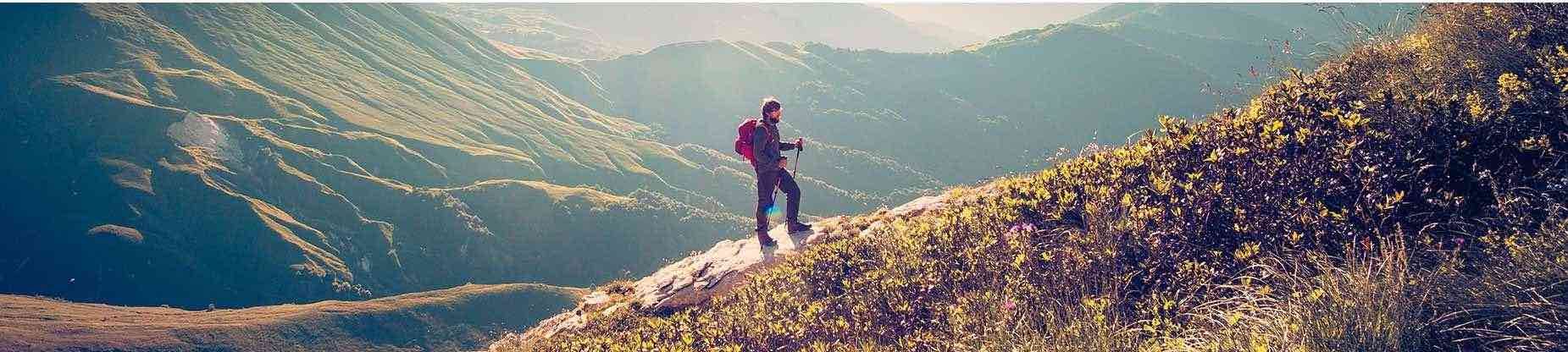 landscape on the top of a mountain with a hiker climbing up the side